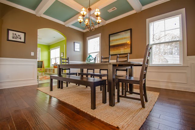 a dining room with a dark rood table and chairs and beige and white walls